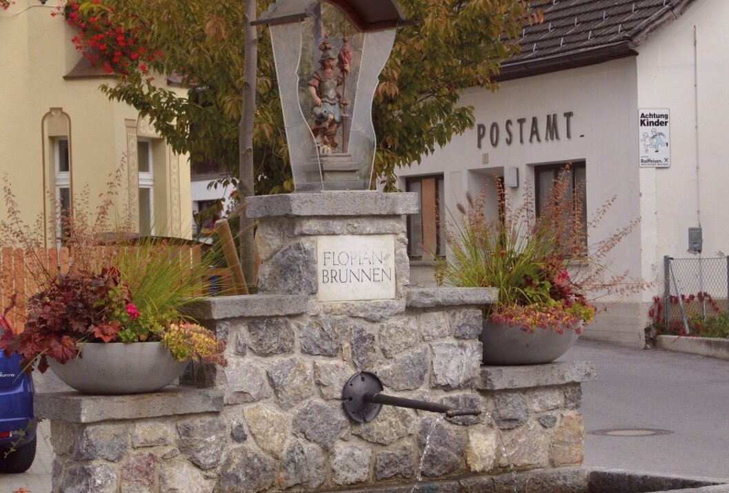 Steinbrunnen vor Gebäude mit Aufschrift Postamt