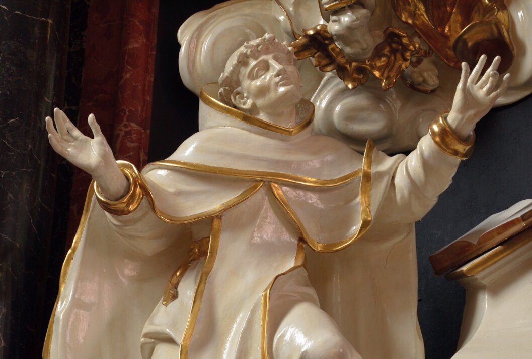 Weiße Heiligenfigur mit goldenen Akzenten, nach oben blickend