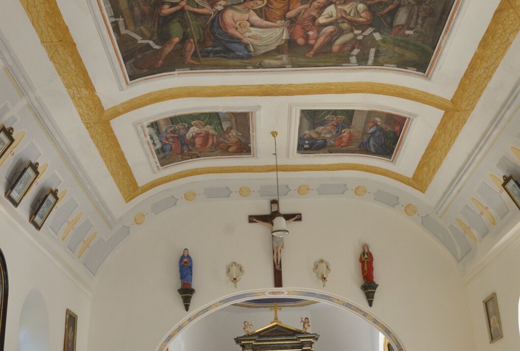 Innenansicht einer Kirche mit Deckenfresko, Kreuz und Altar