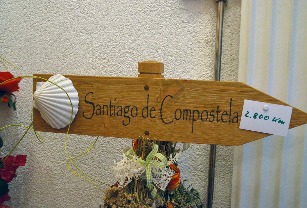 Holzschild mit der Aufschrift Santiago de Compostela und Jakobsmuschel