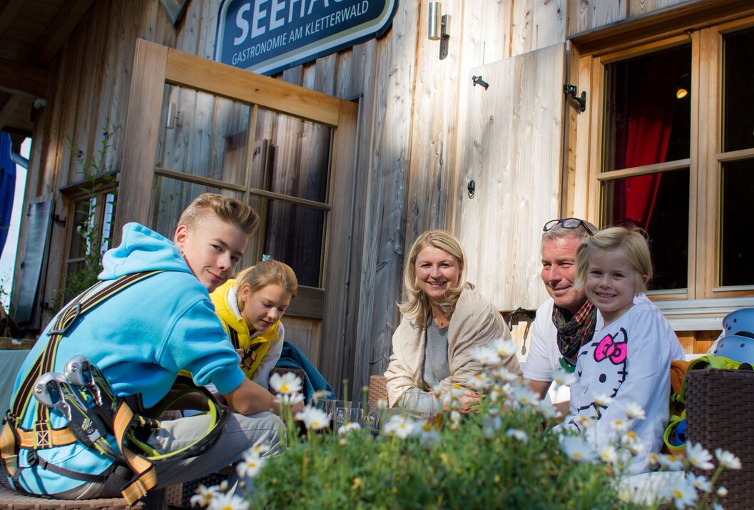 Familie sitzt vor dem Seehaus Gastronomie am Kletterwald