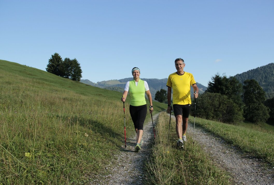 Frau und Mann wandern mit Stöcken auf einem Pfad
