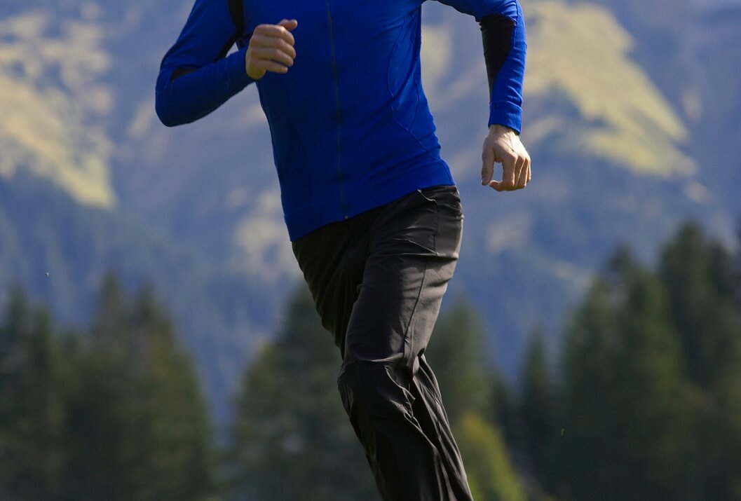 Mann joggt in blauer Sportbekleidung vor Bergkulisse