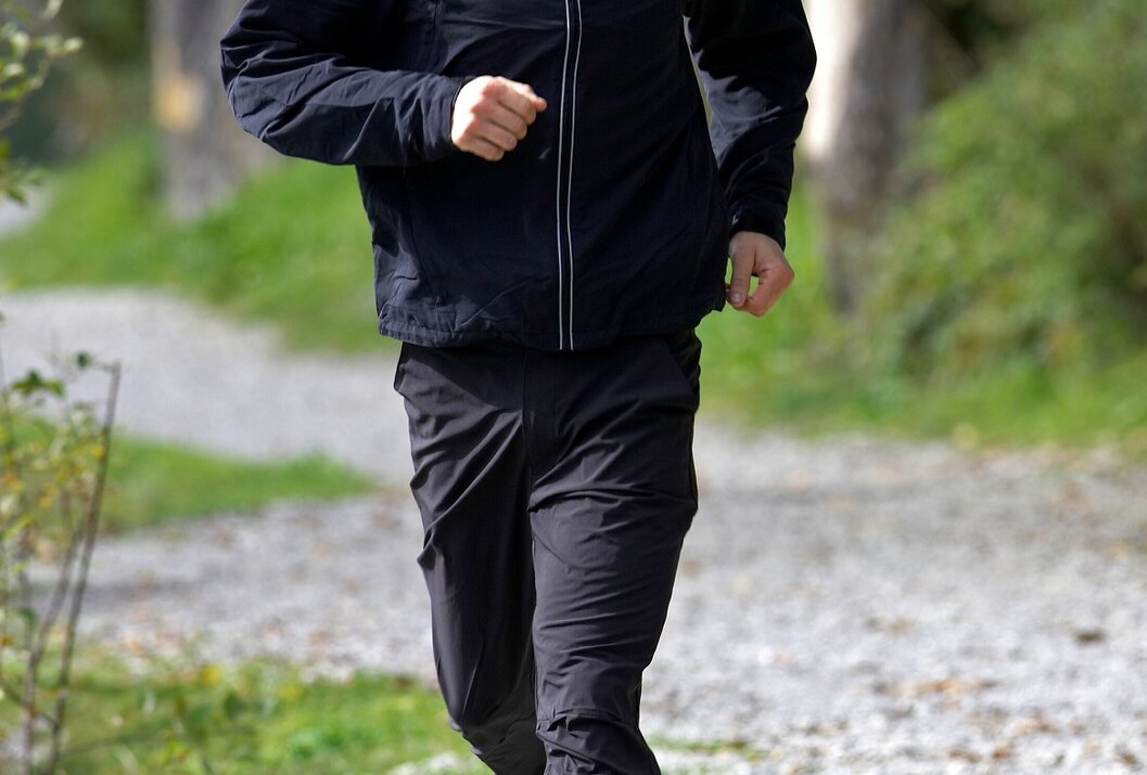 Mann joggt auf Kiesweg im Park