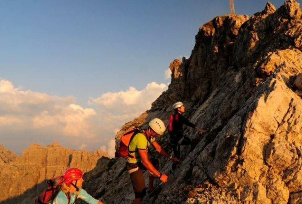 Bergsteiger klettern auf einen felsigen Gipfel mit Kreuz
