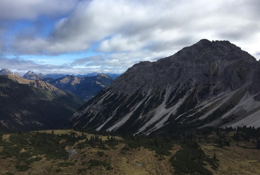 Berglandschaft mit bewaldeten Tälern unter bewölktem Himmel