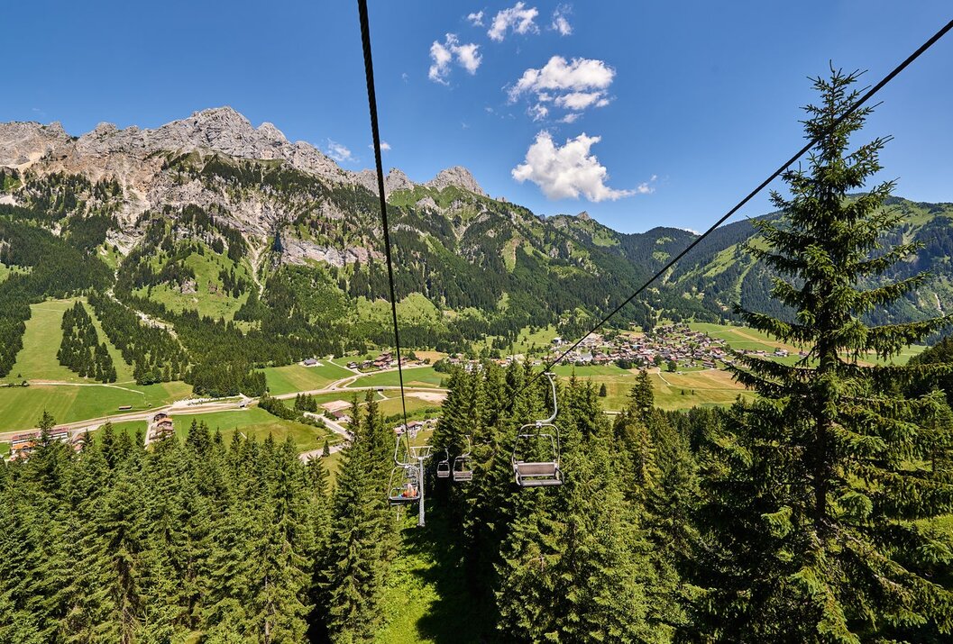 Blick aus Sessellift auf grüne Landschaft mit Bergen und Dorf