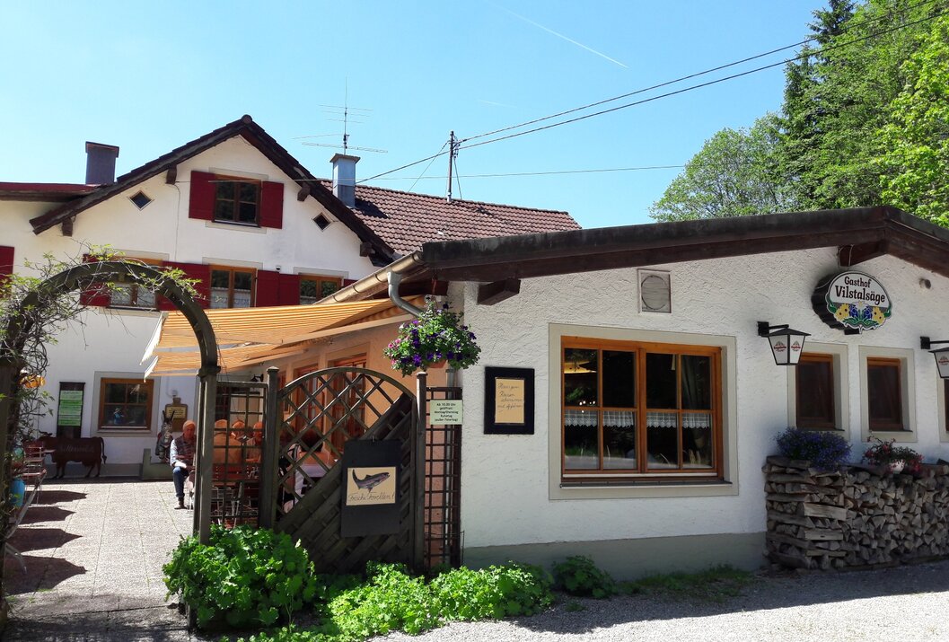 Gasthof mit weißer Fassade, Holztüren und rotem Dach unter blauem Himmel