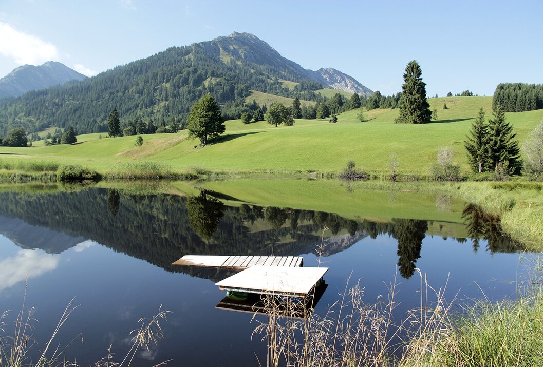 Berglandschaft mit See und kleinem Steg im Vordergrund