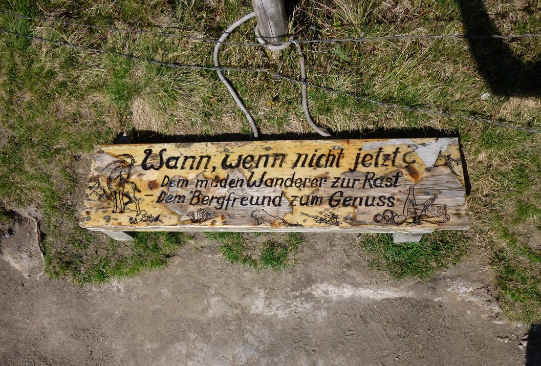 Holzschild mit Aufschrift "Wann, wenn nicht jetzt" und "Dem müden Wanderer zur Rast - Dem Bergfreund zum Genuss"