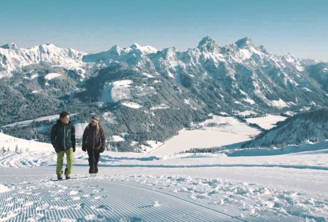 Zwei Personen wandern im Schnee vor schneebedeckten Bergen