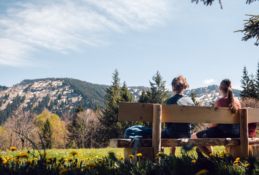 Person sitzt auf Bank mit Blick auf Berglandschaft