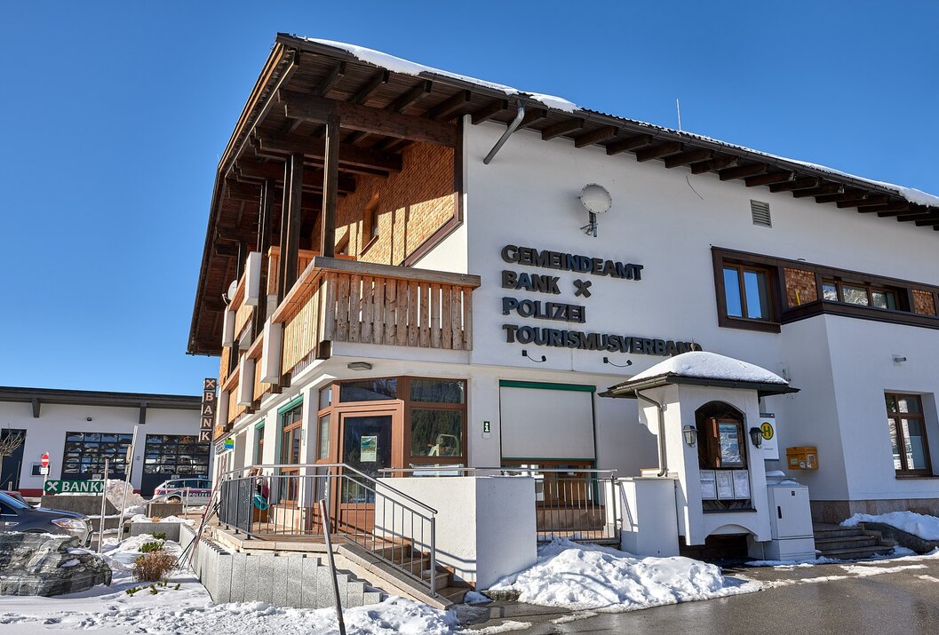 Gebäude mit Aufschrift Gemeindeamt Bank Polizei Tourismusverband im Winter