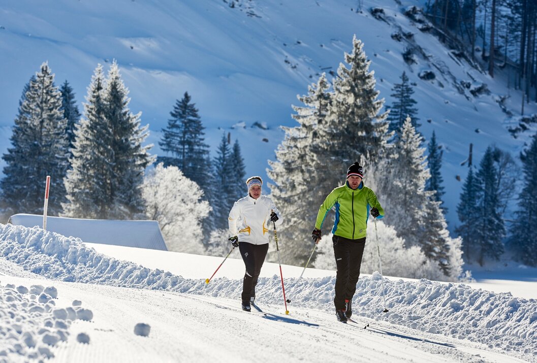 Zwei Personen beim Langlaufen in verschneiter Winterlandschaft
