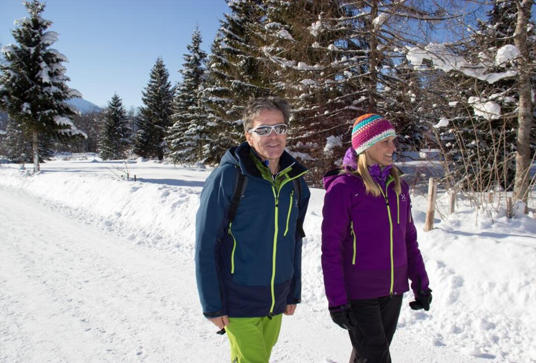 Mann und Frau spazieren im Winter durch eine verschneite Landschaft