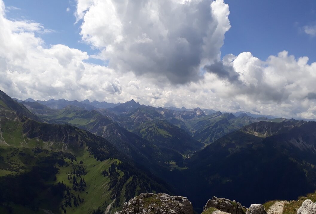 Berglandschaft mit grünen Hängen unter blauem Himmel mit Wolken