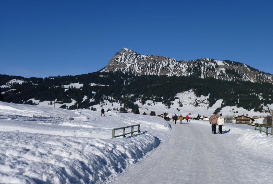 Winterlandschaft mit schneebedecktem Weg, Berg im Hintergrund und einigen Personen