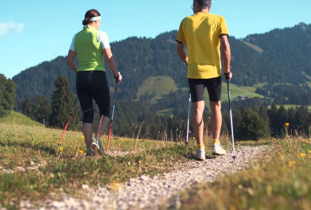Zwei Personen beim Nordic Walking in bergiger Landschaft