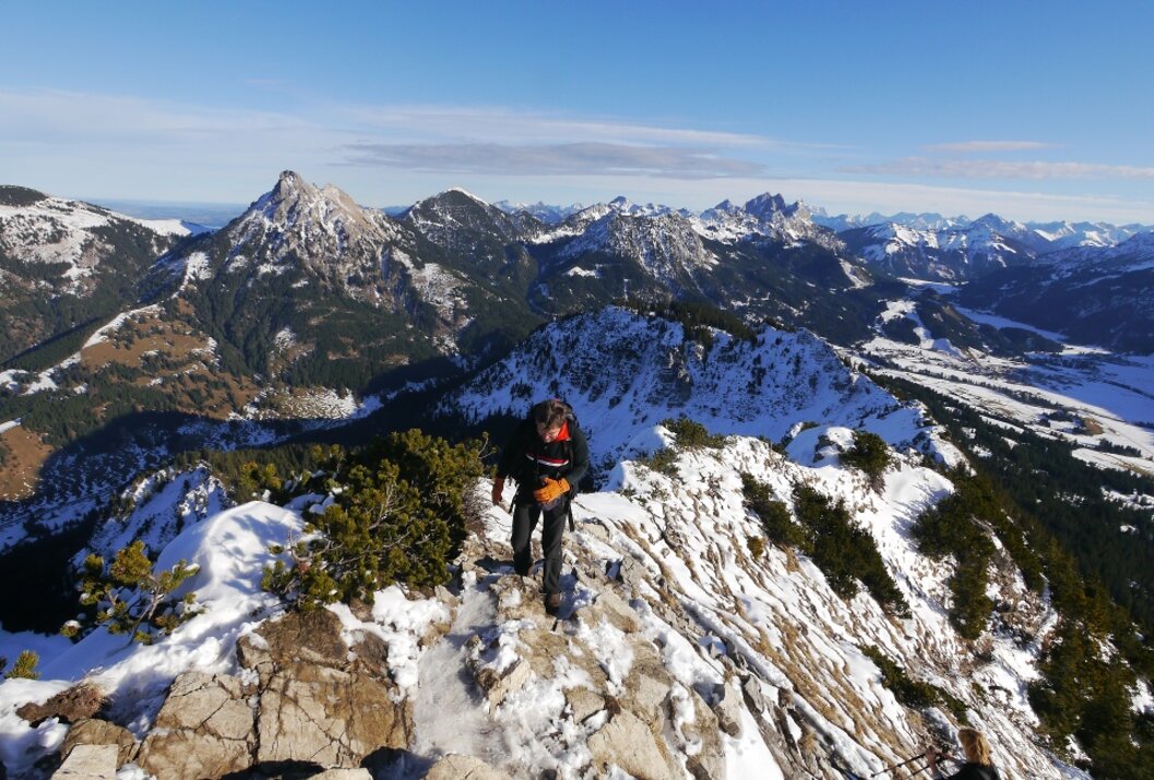 Bergsteiger auf schneebedecktem Grat mit Bergpanorama im Hintergrund