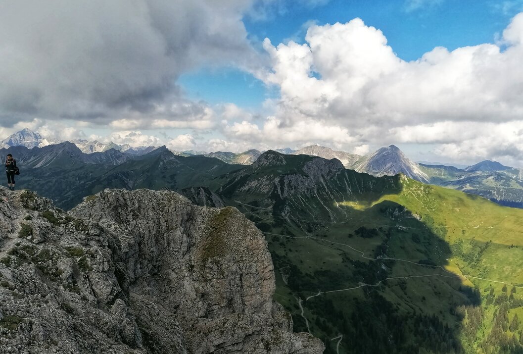 Berglandschaft mit Felsen, grünen Hängen und Wolkenhimmel