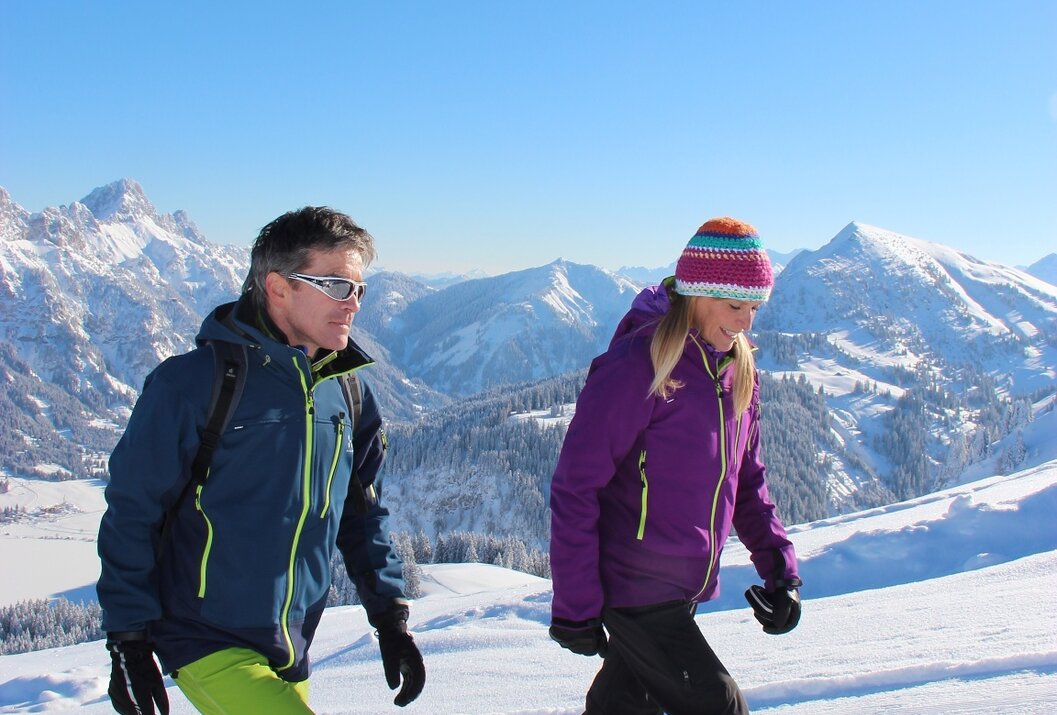 Paar wandert im Schnee vor Bergpanorama