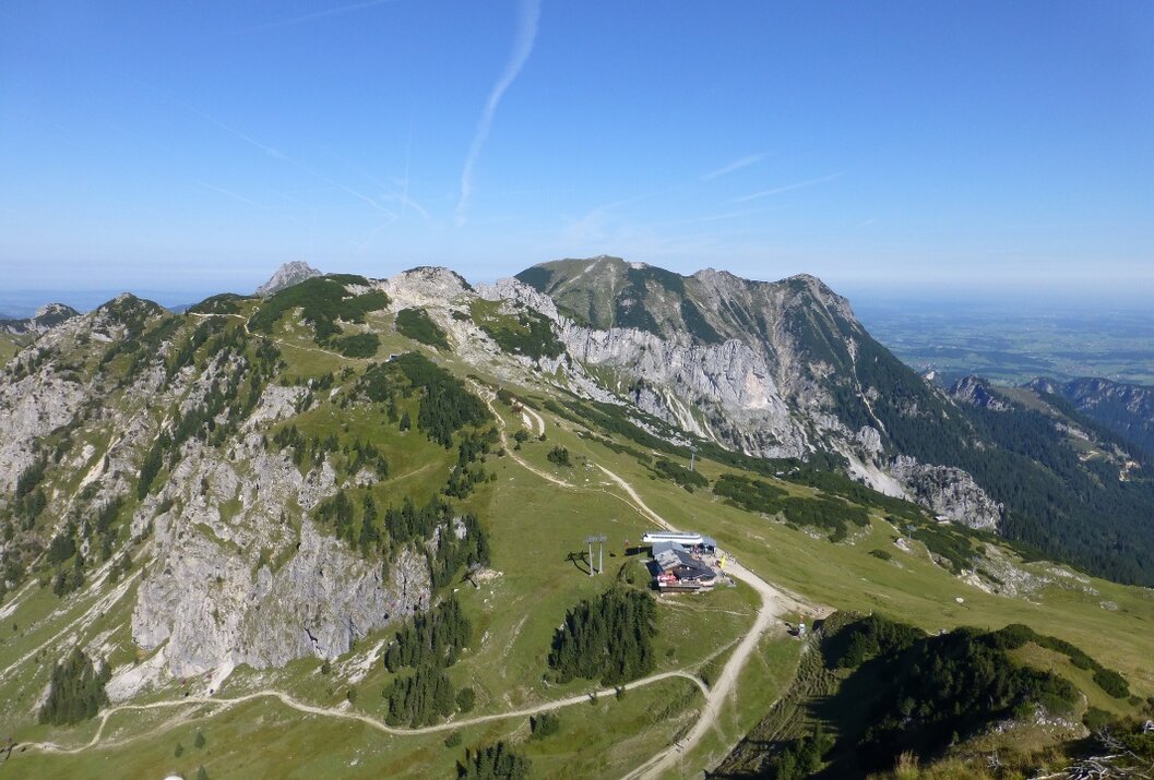 Berglandschaft mit Hütte und Wanderwegen unter blauem Himmel