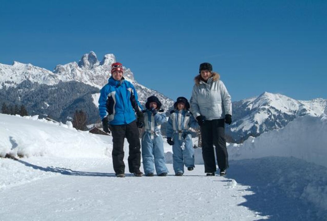 Familie im Schnee vor Bergkulisse