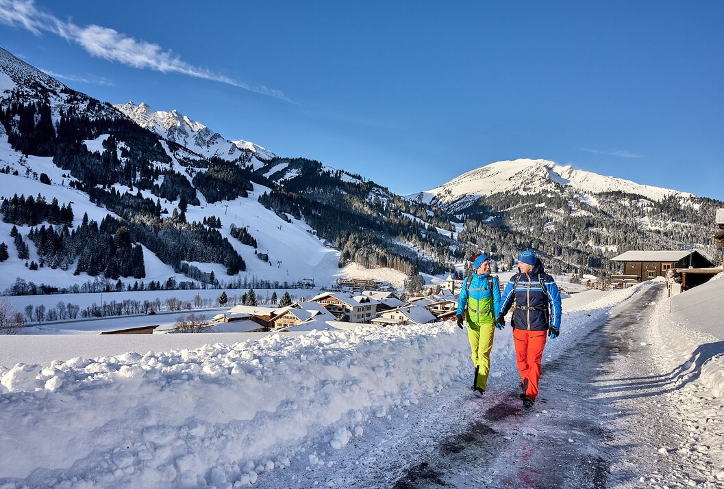Paar Hand in Hand im Winter vor verschneiter Berglandschaft