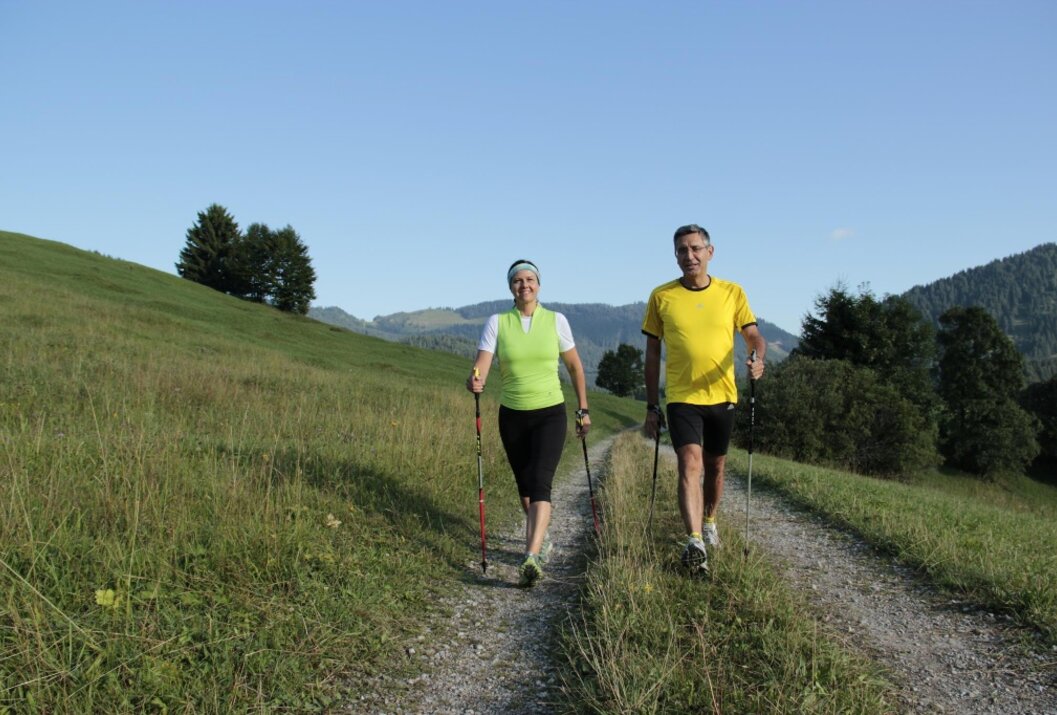 Frau und Mann beim Nordic Walking auf einem Feldweg