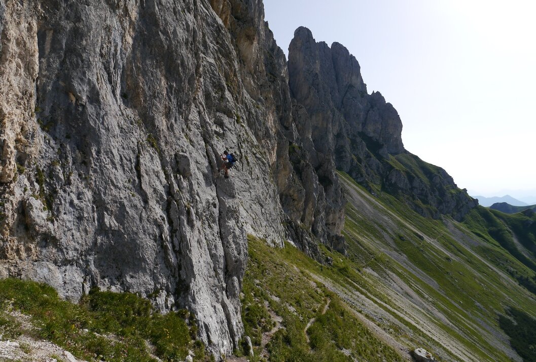 Kletterer an steiler Felswand in bergiger Landschaft