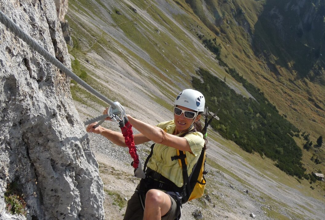 Klettersteiggeher mit Helm und Rucksack am Felsgrat