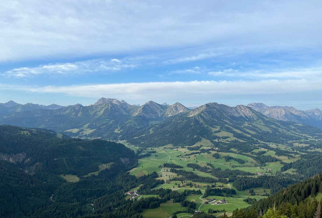 Weite grüne Landschaft mit Bergen unter blauem Himmel