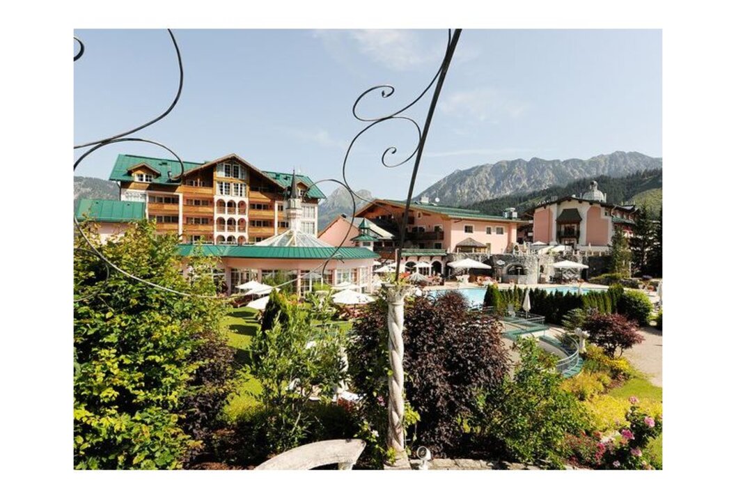 Hotelanlage mit Pool und Garten vor Bergkulisse
