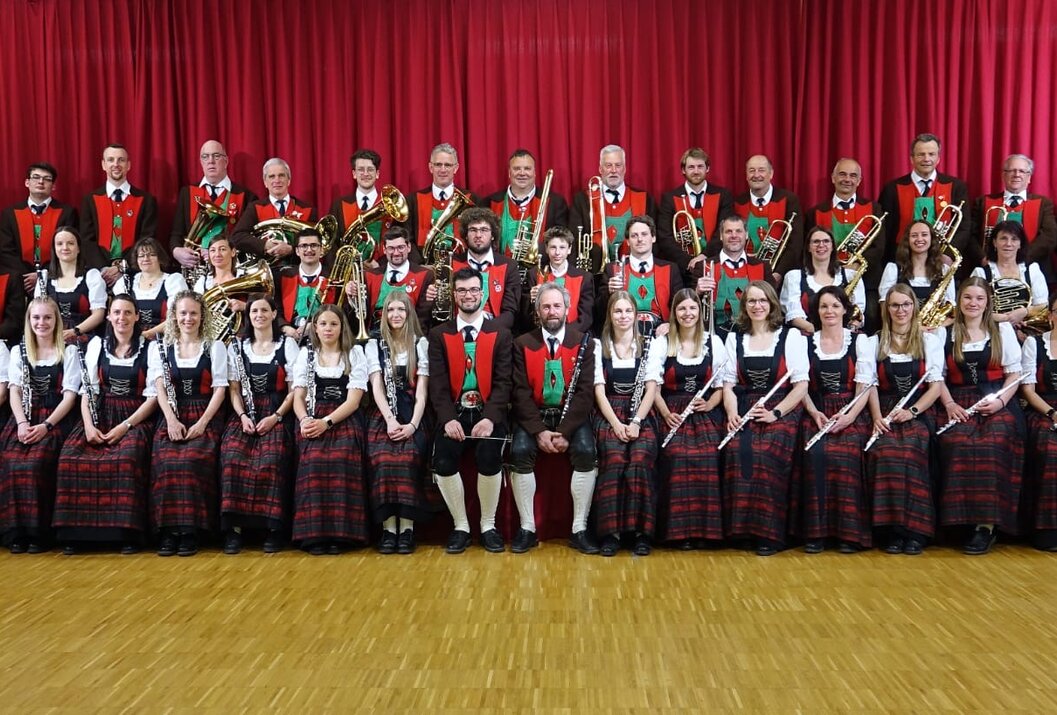 Blasorchester in Tracht vor rotem Vorhang für Gruppenfoto