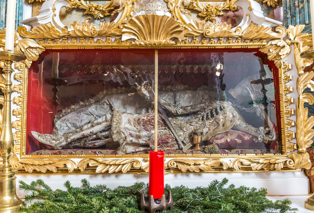 Reliquie in verziertem Glasschrein mit roter Kerze davor