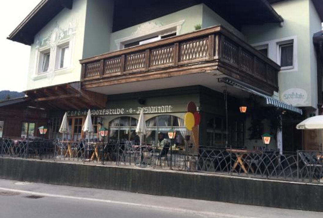 Café-Dorfstube-Restaurant mit Balkon und Tischen im Freien