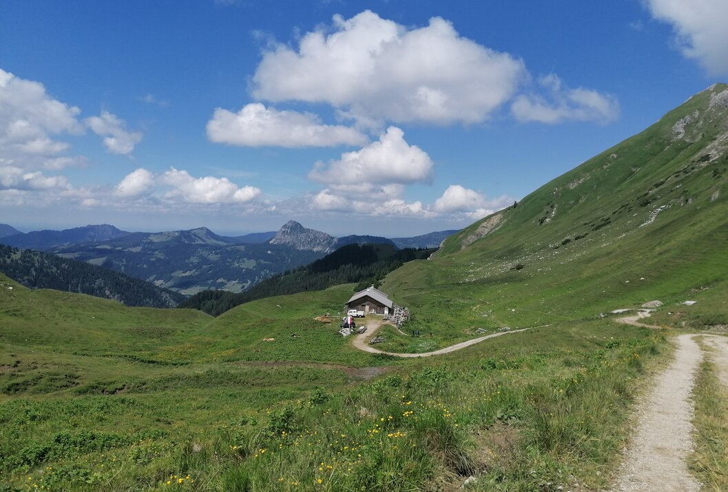 Hütte in grüner Berglandschaft unter blauem Himmel mit Wolken