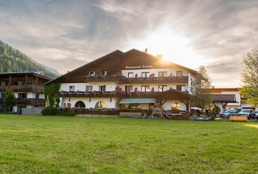 Hotel building with dark roof and green meadow in the foreground in sunshine