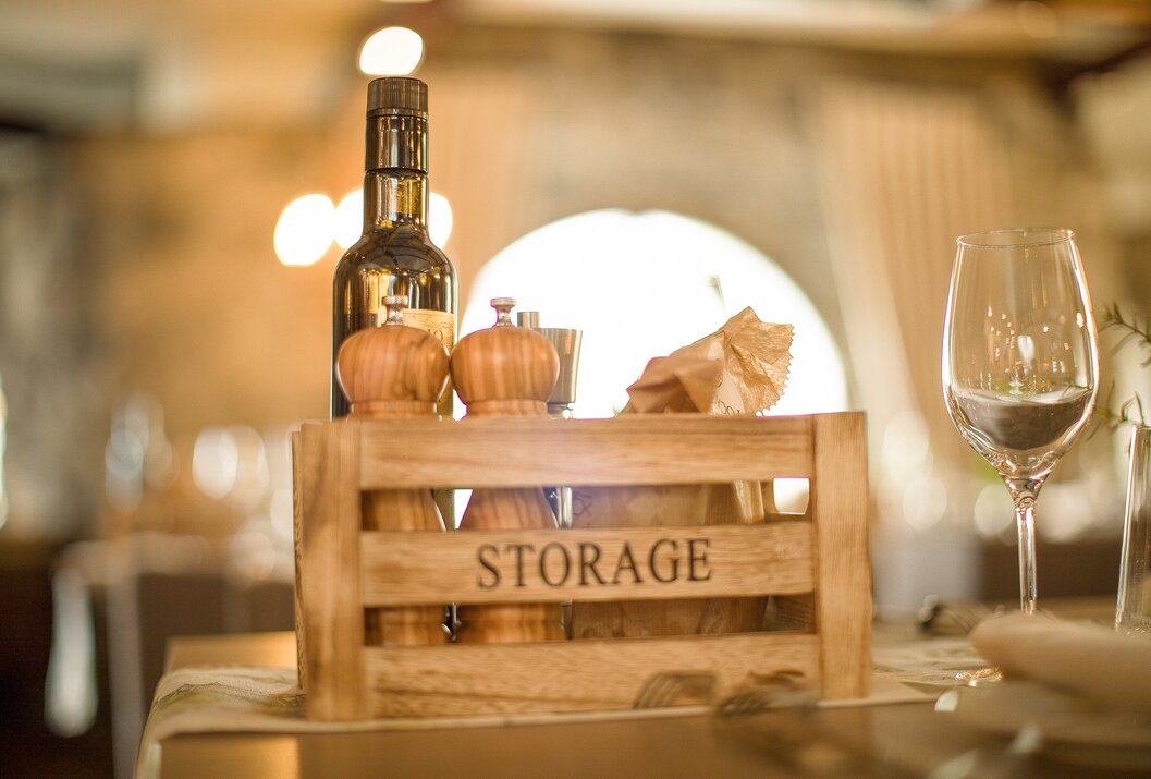 Holzkiste mit Aufschrift STORAGE, Ölflasche und Gewürzstreuer auf einem Tisch