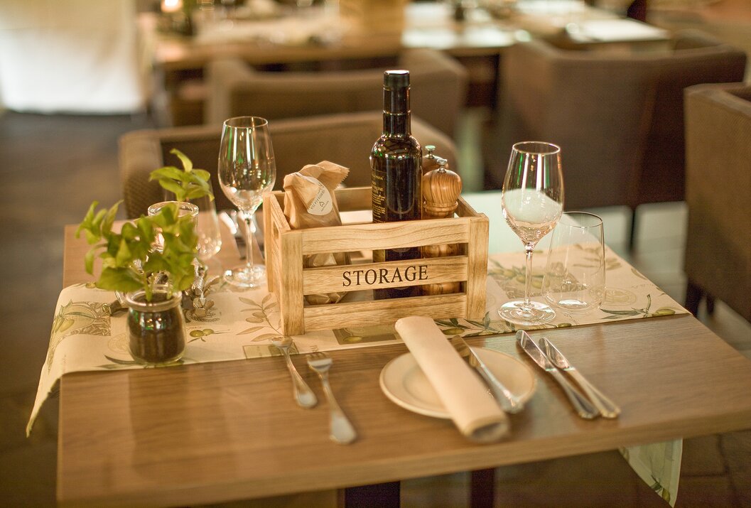 Gedeckter Tisch mit Holzkiste, Gläsern, Ölflasche und Besteck in einem Restaurant