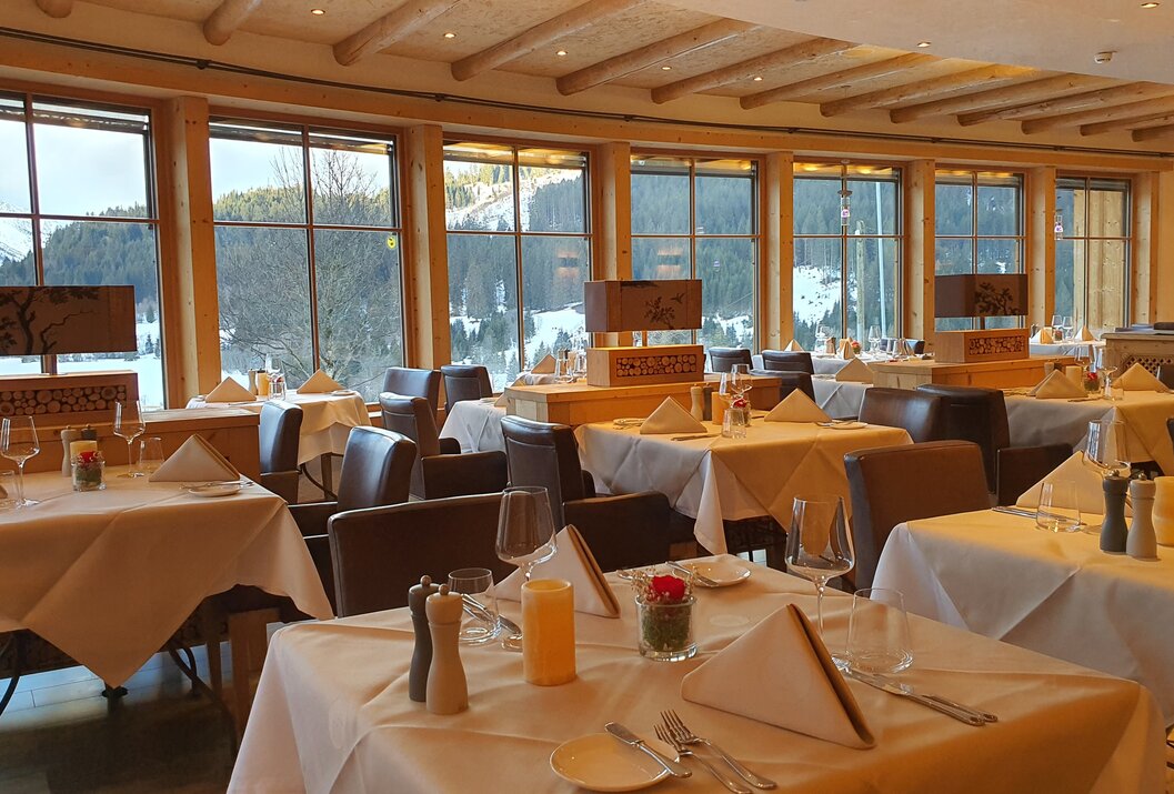 Restaurant mit gedeckten Tischen und Blick auf verschneite Landschaft