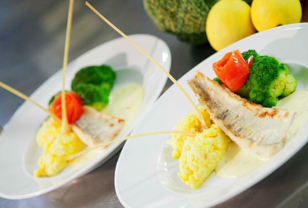 Zwei Teller mit Fisch, Kartoffelpüree, Brokkoli und Tomaten garniert mit langen Spießen