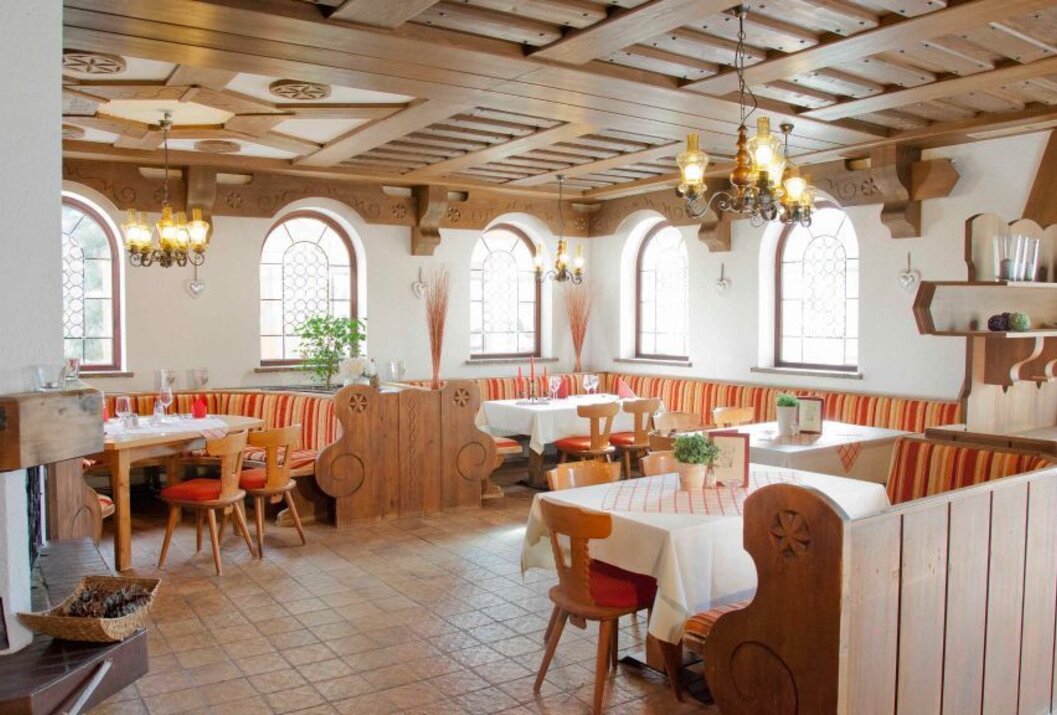 Gemütliches Restaurant mit Holzbalkendecke, hellen Wänden, Bänken und Tischen mit karierten Tischdecken