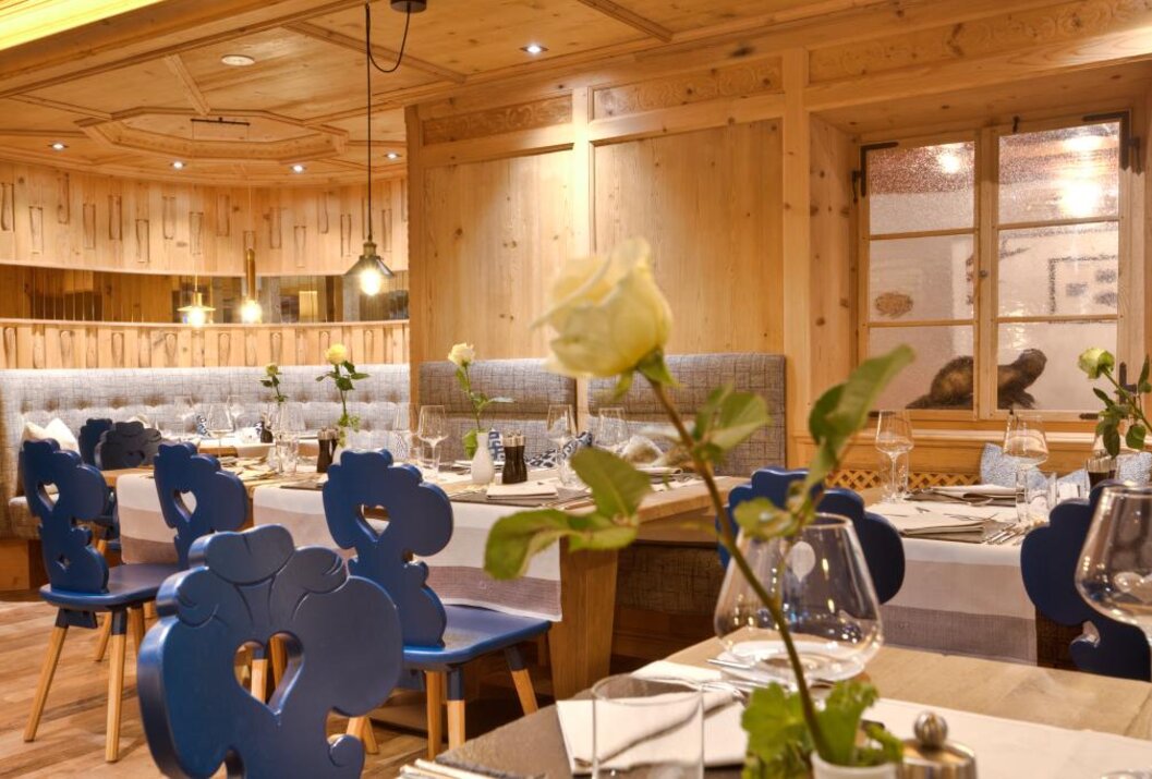 Gemütliches Restaurant mit Holzwänden, gedeckten Tischen und blauen Stühlen