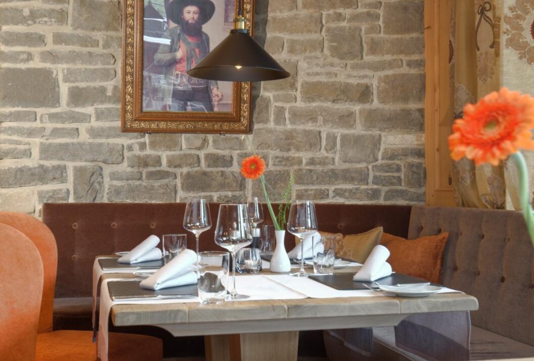 Gedeckter Tisch in rustikalem Restaurant mit Steinwand und Porträt