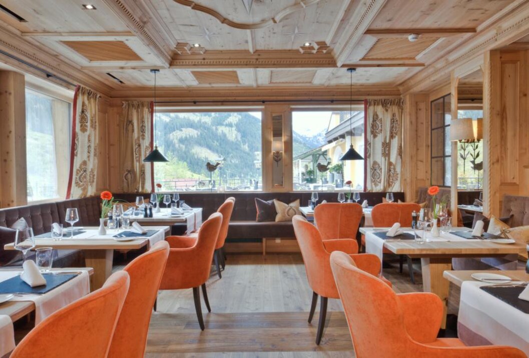 Restaurant mit orangefarbenen Sesseln, gedeckten Tischen und Blick auf Berge