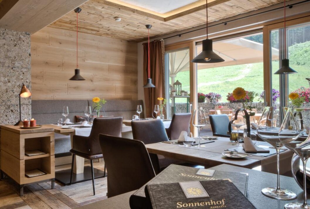 Restaurant mit gedeckten Tischen, Blick ins Grüne und Speisekarte im Vordergrund