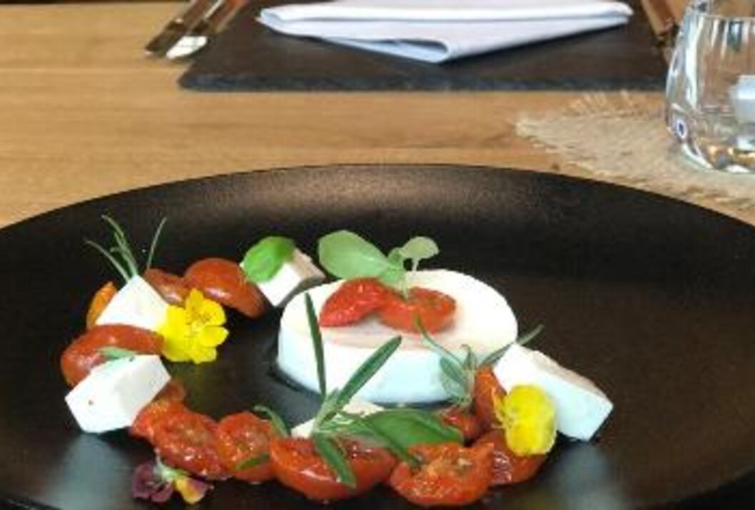 Mozzarella mit Tomaten und Kräutern auf schwarzem Teller