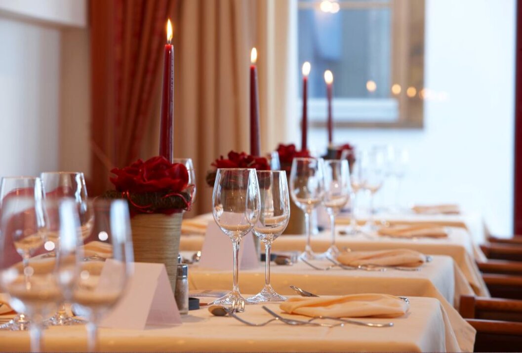 Gedeckter Tisch mit Kerzen, Gläsern, Servietten und Blumenschmuck