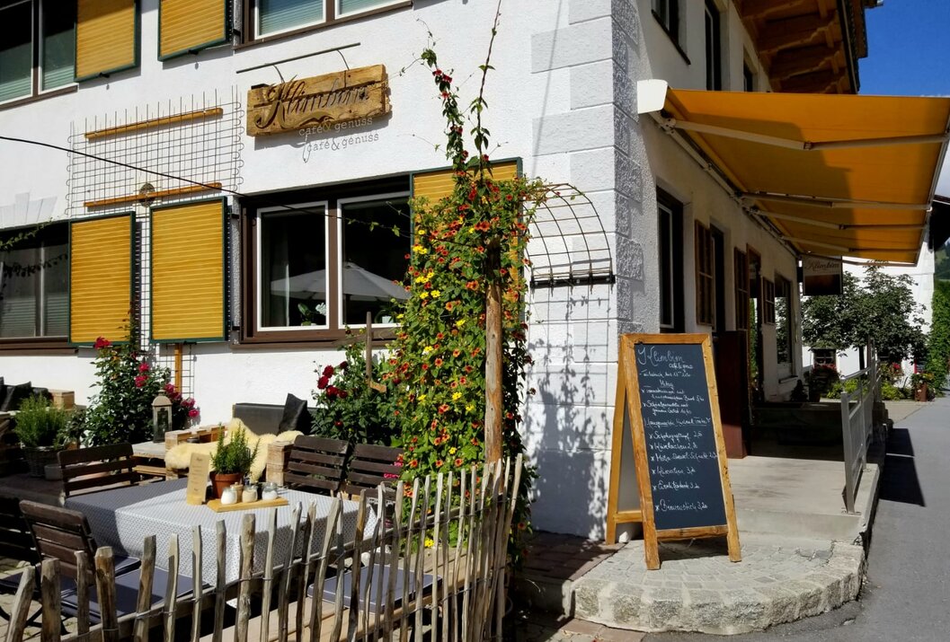 Restaurant mit gelben Fensterläden, Speisekarte und Außenterrasse